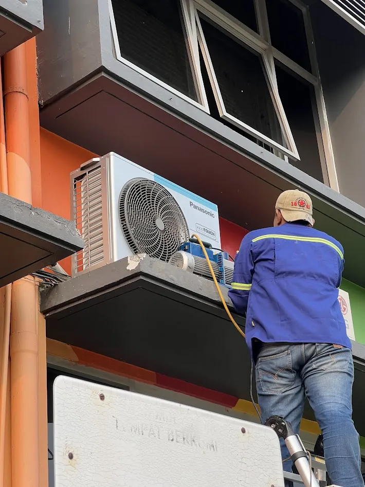 Teknisi melakukan proses vakum pada unit luar AC Panasonic sebelum refrigerant dilepaskan